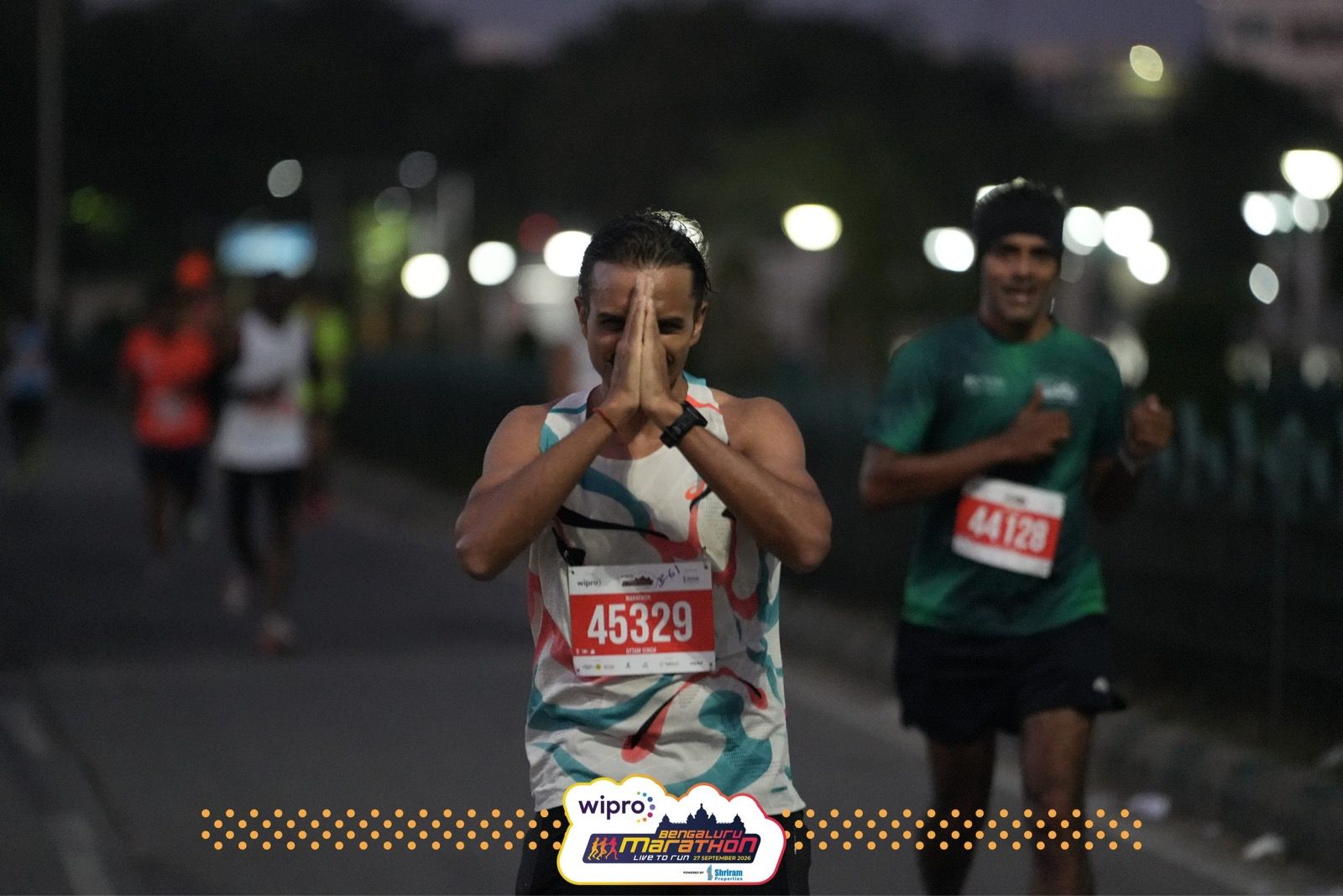 Uttam, bib 45329, runs toward the camera in the pre-dawn dark with his palms pressed together in a namaste.