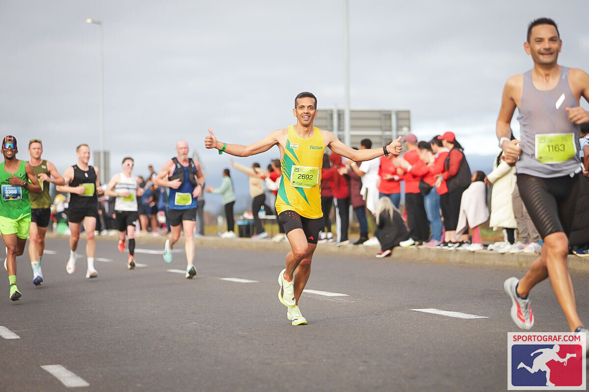 Vijay running with arms outstretched in a crowded mid-race section.